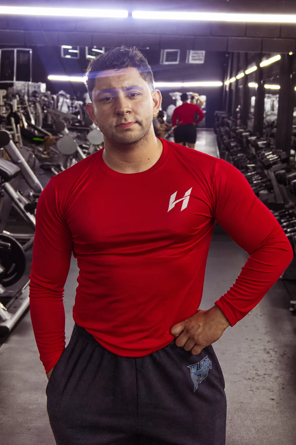Atleta Hustform con camiseta roja de manga larga, mano en la cintura