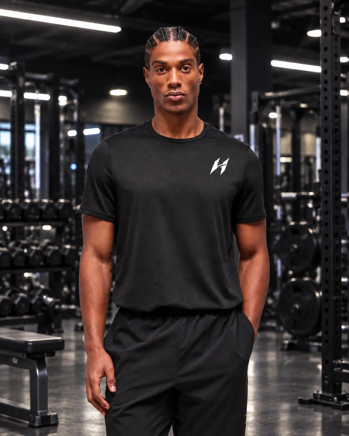 Atleta Hustform de pie con camiseta negra frente a un fondo oscuro